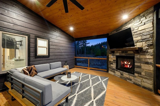 living room featuring vaulted ceiling, an outdoor stone fireplace, ceiling fan, wooden ceiling, and hardwood / wood-style flooring