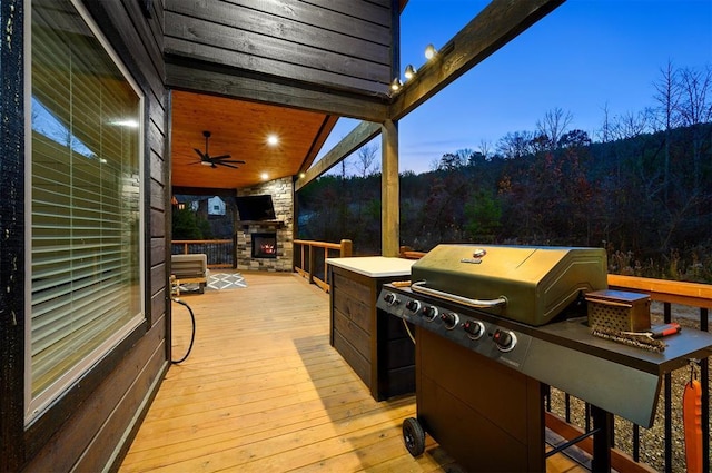 deck featuring ceiling fan and an outdoor stone fireplace