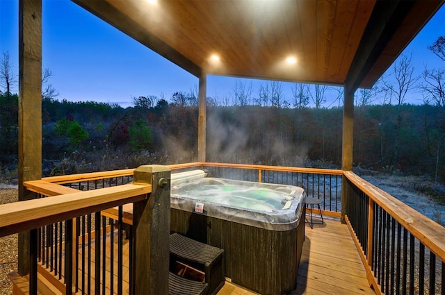 deck at dusk featuring a hot tub