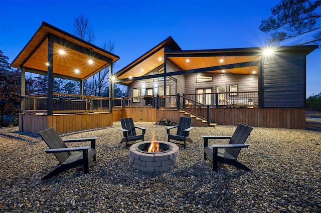 patio terrace at dusk featuring a wooden deck and an outdoor fire pit