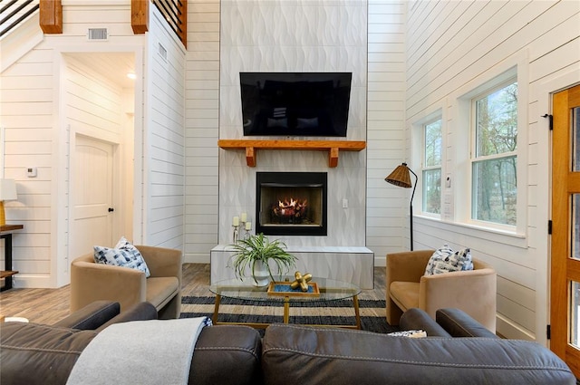 living room with a fireplace, hardwood / wood-style floors, and wooden walls