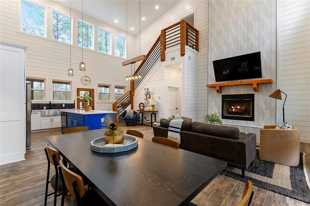 dining space with dark hardwood / wood-style flooring, a large fireplace, high vaulted ceiling, and plenty of natural light