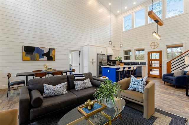 living room with wood-type flooring, a towering ceiling, and sink