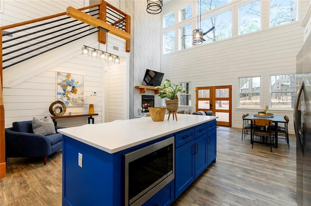 kitchen with blue cabinetry, a towering ceiling, a kitchen island, and plenty of natural light