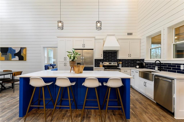 kitchen with decorative light fixtures, a kitchen island, a towering ceiling, and appliances with stainless steel finishes