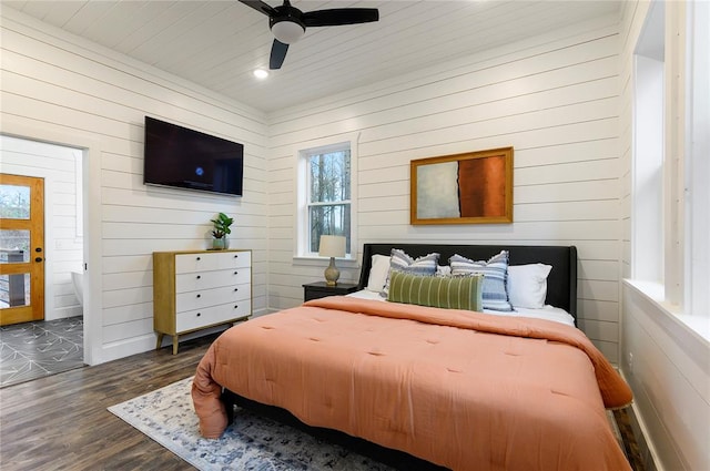 bedroom featuring dark hardwood / wood-style flooring, ceiling fan, and wood walls