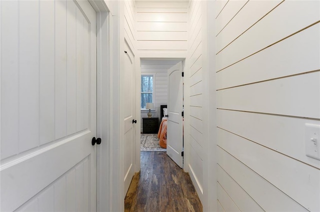 hall with dark hardwood / wood-style flooring and wooden walls