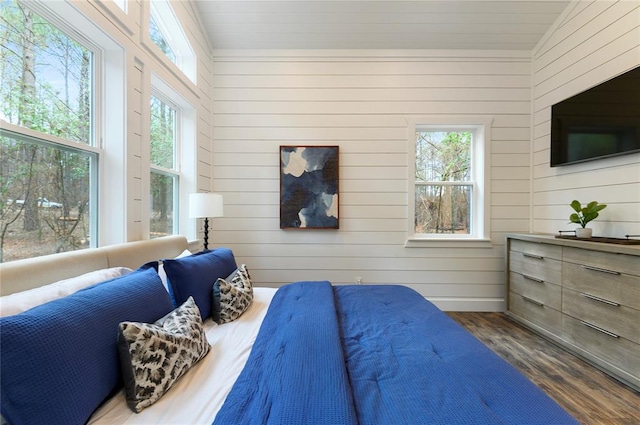 bedroom with multiple windows, wooden walls, dark wood-type flooring, and vaulted ceiling