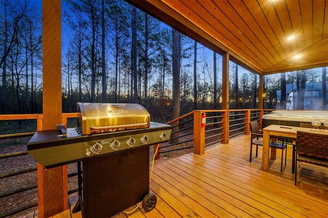 deck at dusk featuring area for grilling and a jacuzzi