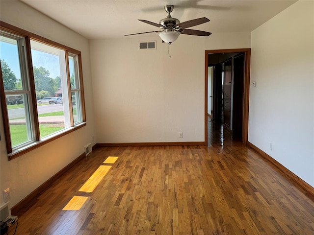 unfurnished room featuring a wealth of natural light, ceiling fan, and dark wood-type flooring