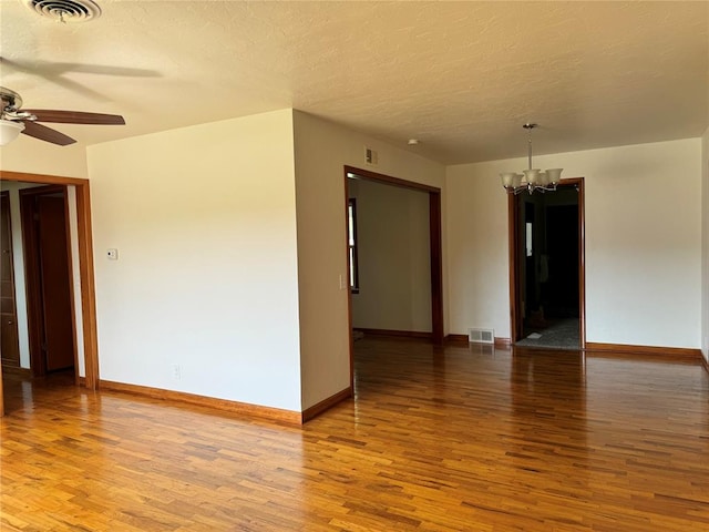 spare room with ceiling fan with notable chandelier, wood-type flooring, and a textured ceiling