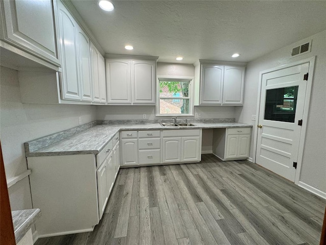 kitchen featuring a textured ceiling, light hardwood / wood-style flooring, white cabinetry, and sink