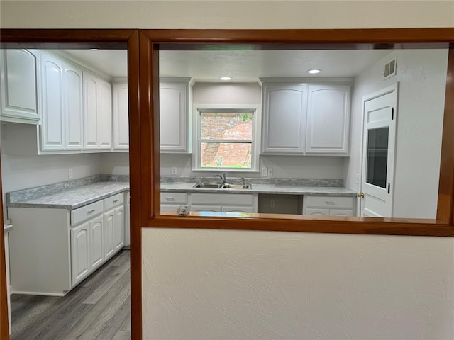 kitchen with sink, white cabinets, and light hardwood / wood-style flooring