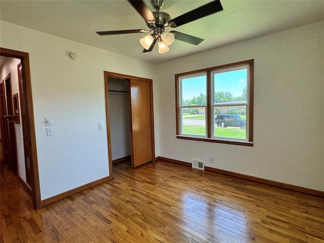 unfurnished bedroom with wood-type flooring, a closet, and ceiling fan