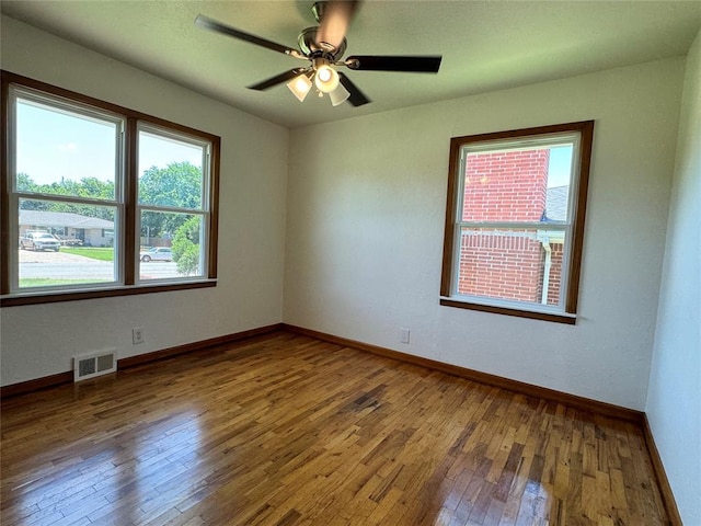 empty room featuring ceiling fan, wood-type flooring, and a wealth of natural light