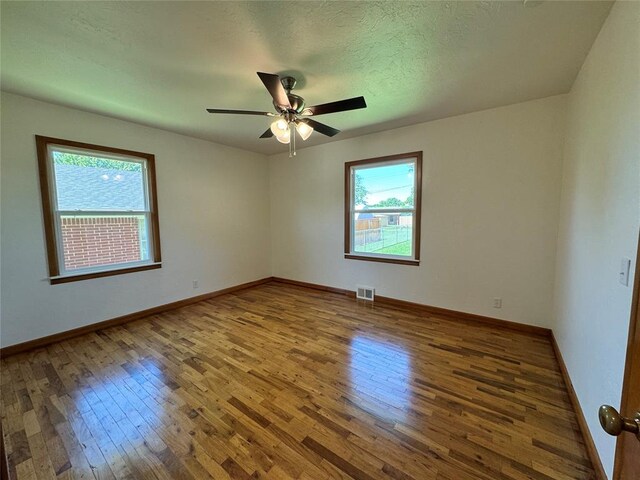 unfurnished room with hardwood / wood-style floors, ceiling fan, a healthy amount of sunlight, and a textured ceiling