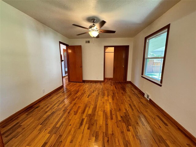 unfurnished bedroom with a textured ceiling, hardwood / wood-style flooring, and ceiling fan