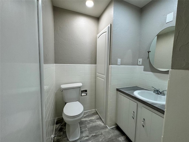 bathroom with vanity, toilet, and tile walls