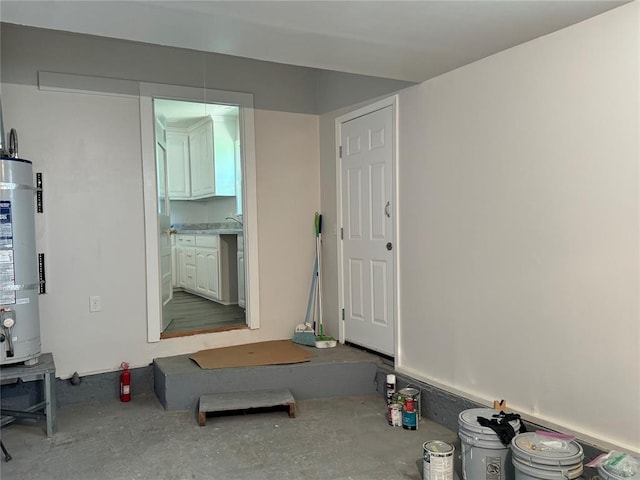 interior space with water heater, sink, and concrete flooring