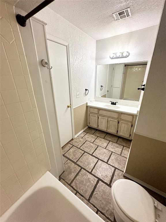 full bathroom with shower / bathing tub combination, vanity, a textured ceiling, and toilet