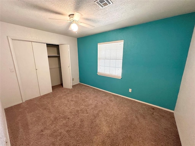 unfurnished bedroom with a textured ceiling, carpet floors, a closet, and ceiling fan