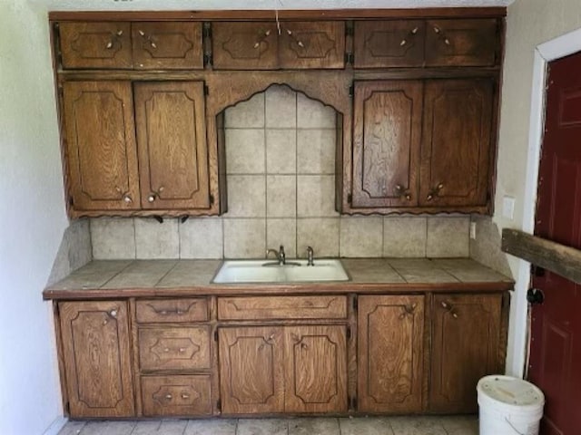 kitchen with decorative backsplash, tile counters, and sink