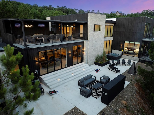 back house at dusk featuring an outdoor living space and a balcony