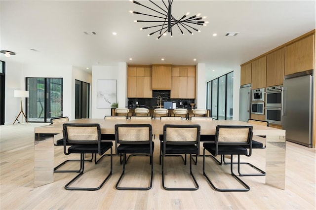 kitchen with backsplash, an inviting chandelier, appliances with stainless steel finishes, a large island, and light hardwood / wood-style floors