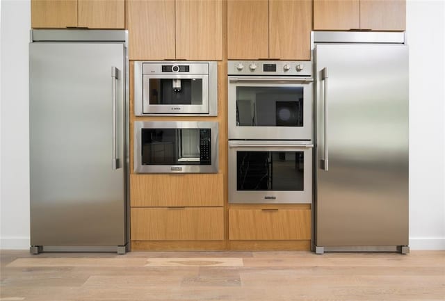 kitchen featuring light brown cabinetry, light wood-type flooring, and appliances with stainless steel finishes