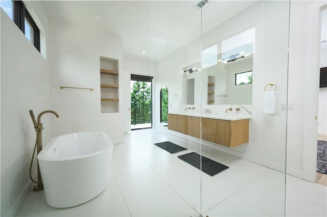 bathroom with a washtub, vanity, and tile patterned flooring