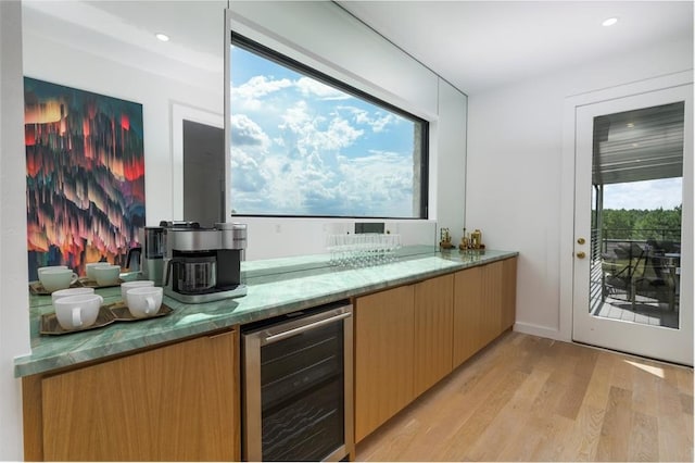 bar featuring a wealth of natural light, light hardwood / wood-style floors, stone countertops, and wine cooler