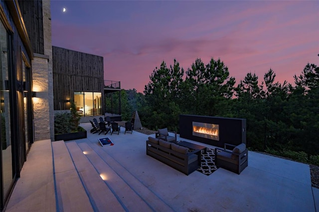 patio terrace at dusk with an outdoor living space with a fireplace