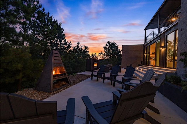 patio terrace at dusk featuring a balcony