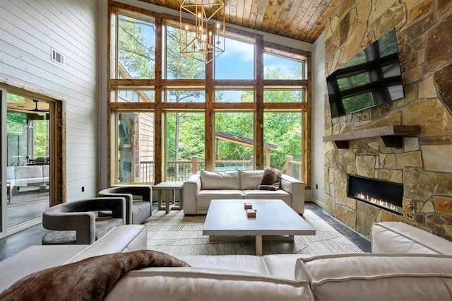 living room featuring a healthy amount of sunlight, an inviting chandelier, high vaulted ceiling, a fireplace, and wood ceiling