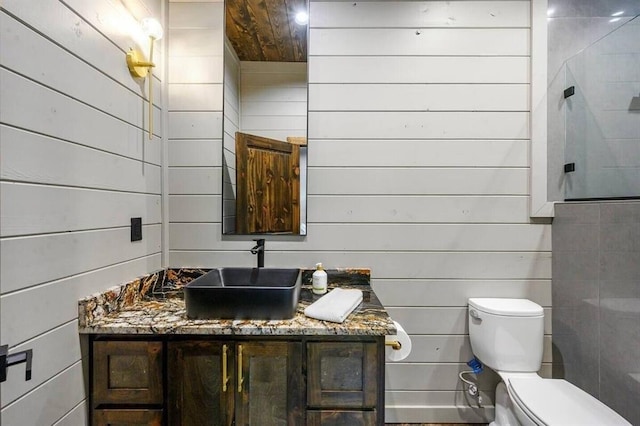 bathroom featuring toilet, vanity, and wooden walls