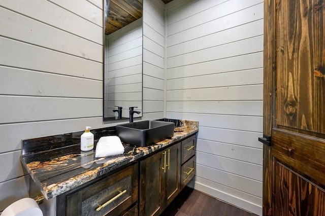 bathroom featuring hardwood / wood-style flooring, vanity, and wood walls