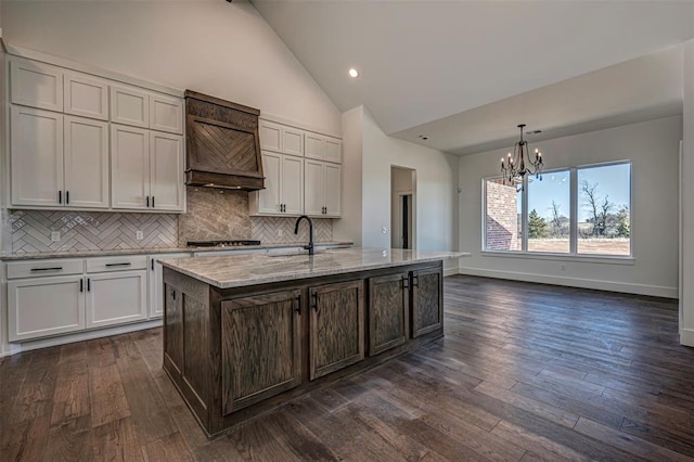 kitchen featuring a center island with sink, dark hardwood / wood-style floors, pendant lighting, and a chandelier