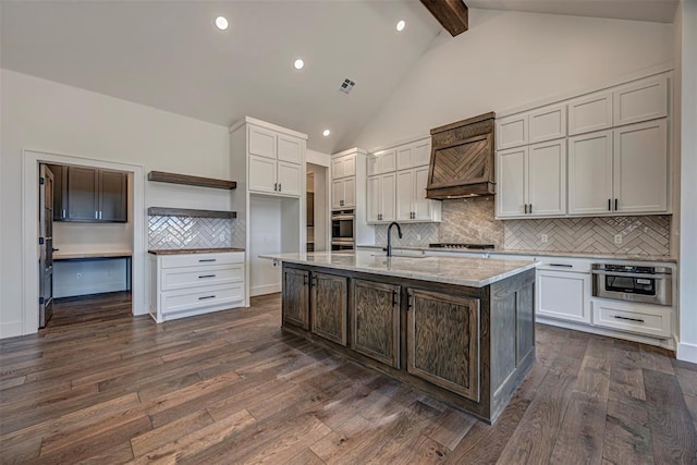 kitchen featuring backsplash, a kitchen island with sink, and dark wood-type flooring