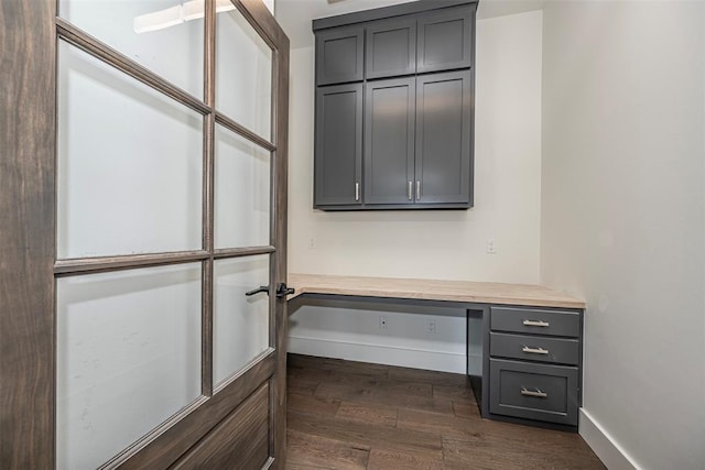 unfurnished office featuring built in desk and dark wood-type flooring