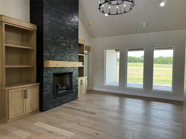 unfurnished living room featuring a fireplace, high vaulted ceiling, a chandelier, and light hardwood / wood-style flooring