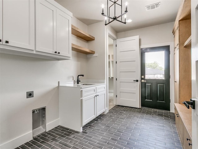 laundry room with electric dryer hookup, cabinets, sink, and an inviting chandelier