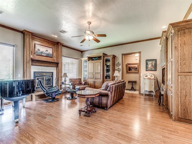 living room with a textured ceiling, light hardwood / wood-style flooring, ceiling fan, and crown molding