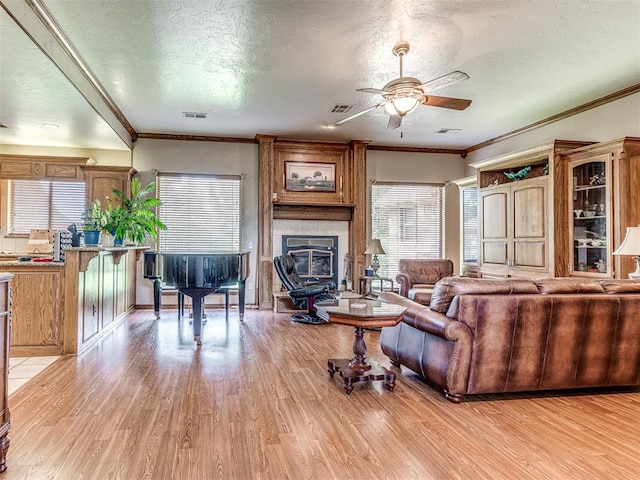 living room with light hardwood / wood-style floors, ornamental molding, and a textured ceiling