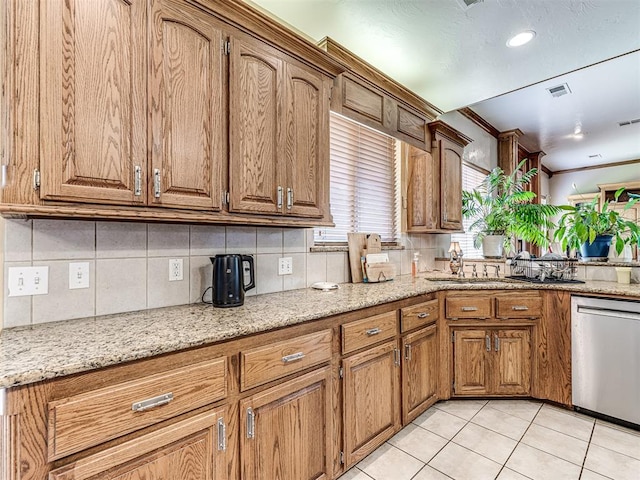 kitchen featuring tasteful backsplash, light stone counters, ornamental molding, light tile patterned floors, and dishwasher