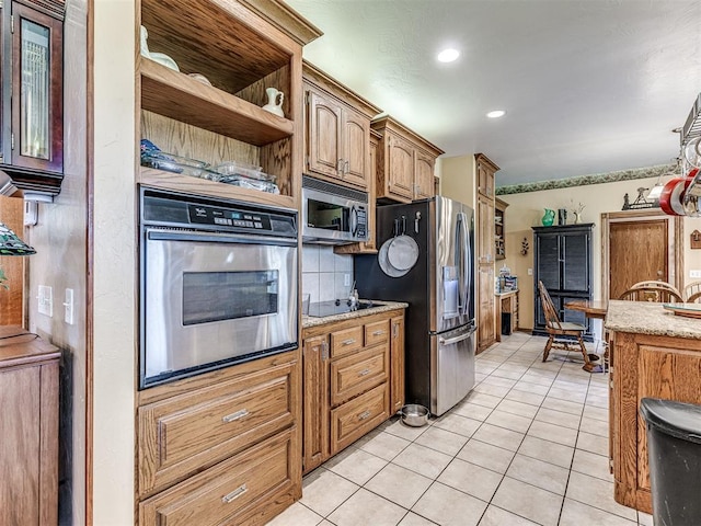 kitchen featuring decorative backsplash, light tile patterned floors, light stone counters, and appliances with stainless steel finishes