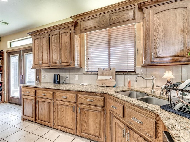 kitchen featuring light stone counters, light tile patterned floors, sink, and tasteful backsplash