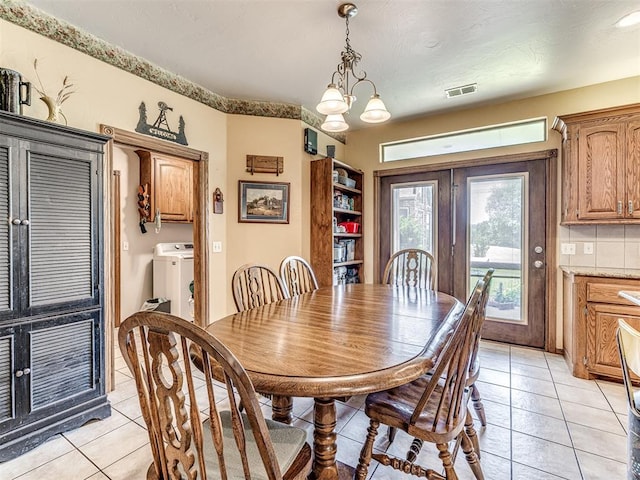 tiled dining area with french doors, washer / clothes dryer, and a chandelier