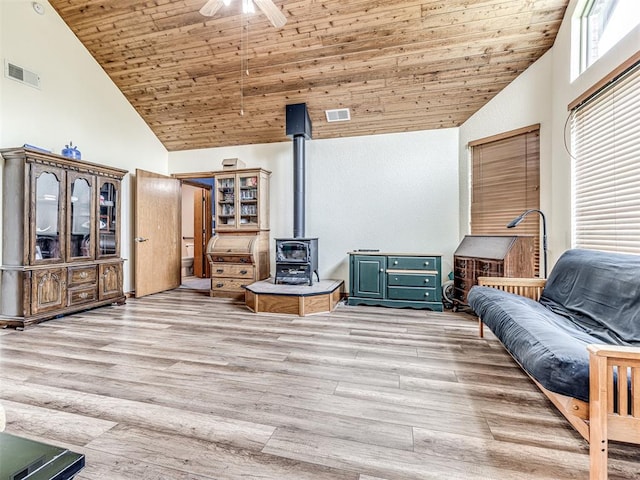 sitting room featuring light wood-type flooring, a wood stove, high vaulted ceiling, and wooden ceiling