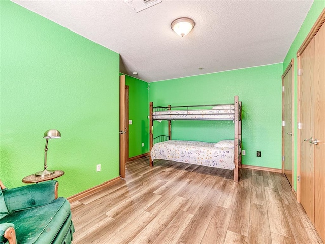 bedroom with a textured ceiling and light wood-type flooring