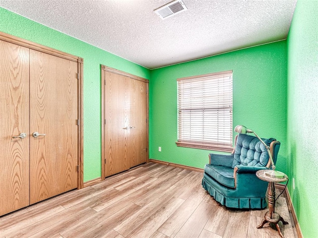 sitting room with light hardwood / wood-style floors and a textured ceiling